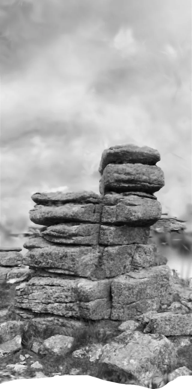 Black and white view of a granite tor, stacked slabs of weathered rock against cloud, with a torn lower edge.